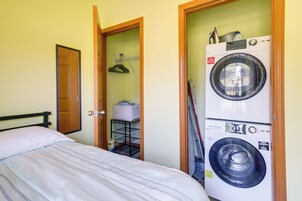 Habitación de hotel pequeña con cama, lavadora y un armario con tendedero.