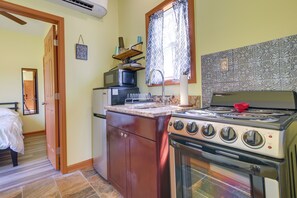Uma cozinha compacta com fogão, forno, micro-ondas e uma geladeira pequena.