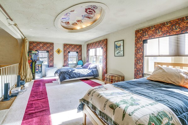 A bedroom with two beds, a ceiling fan, and patterned wallpaper.