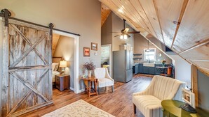 Een ruime loft met een hoge plafond, houten vloeren, een schuifdeur in boerderijstijl, een eethoek en een keuken met moderne apparatuur.