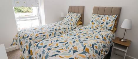 Un dormitorio con cama, mesita de noche, lámpara y ventana con persianas.
