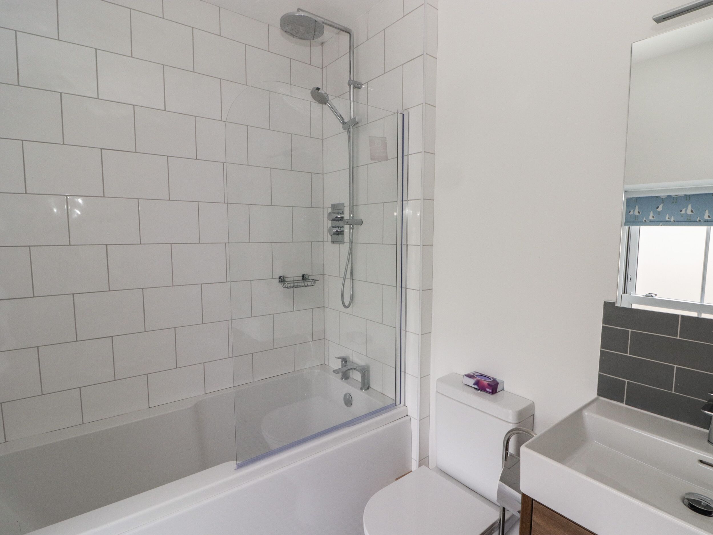 Un bagno moderno con cabina doccia in vetro, un WC bianco e un lavandino con specchio.