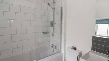 Un bagno moderno con cabina doccia in vetro, un WC bianco e un lavandino con specchio.