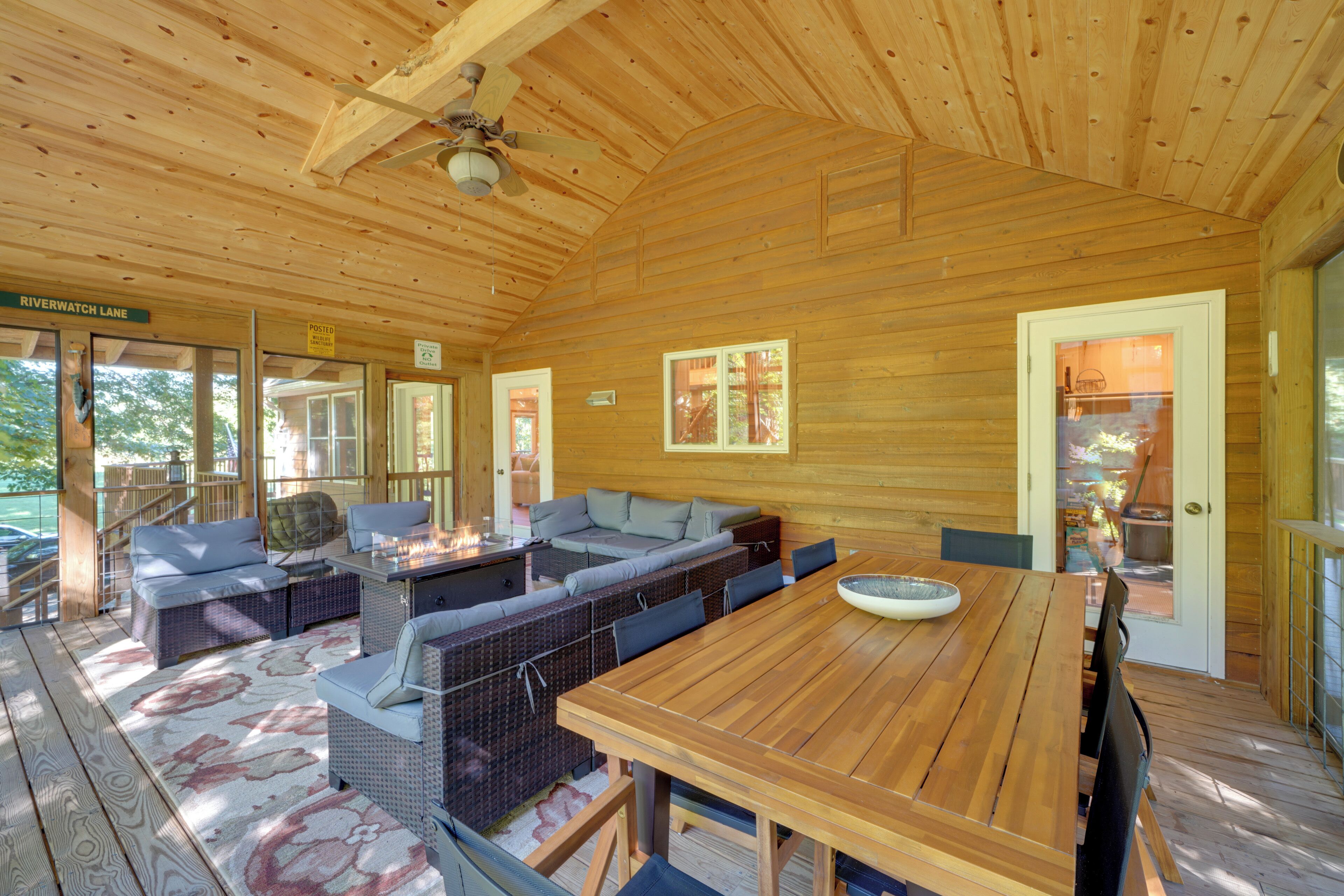 A wooden cabin with a large dining table, built-in seating, and a ceiling fan.