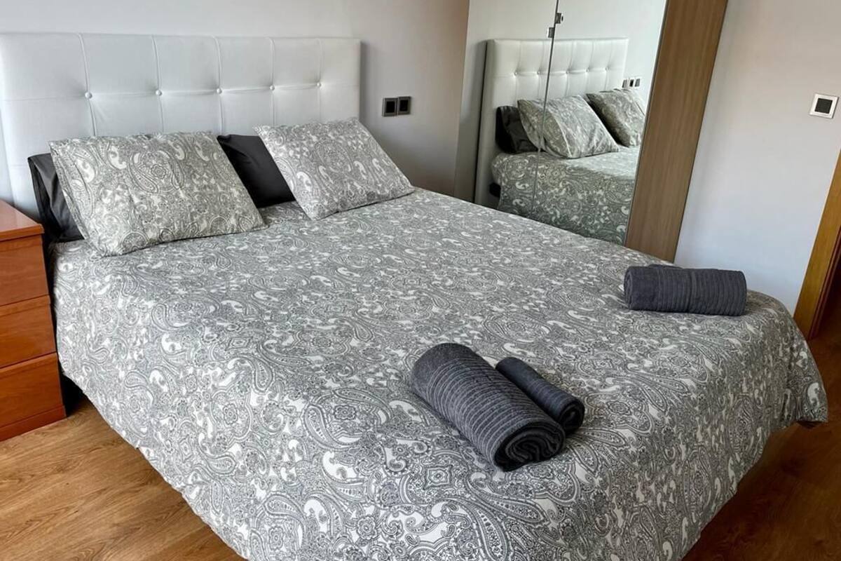 Un lit double avec une couvre-lit à motifs, deux oreillers et des serviettes enroulées.