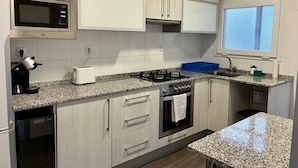 A modern kitchen with granite countertops, stainless steel appliances, and light wood cabinets. - Amplio apartamento cerca FIRA y Centro (L'Hospitalet de Llobregat)