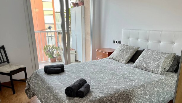 A bedroom with a patterned bedspread, a headboard, and a chair. - Amplio apartamento cerca FIRA y Centro (L'Hospitalet de Llobregat)