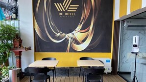 Ristorante del De Hotel Phoen con un design moderno, caratterizzato da un grande logo sulla parete, pavimento in legno e sedie nere intorno a un tavolo.