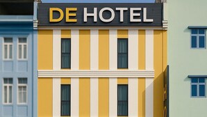 Un hotel a più piani con facciata gialla e un cartello con la scritta "DE HOTEL".