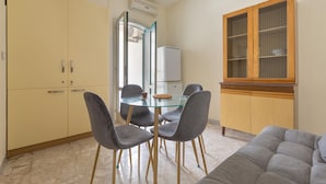 Un espace de vie compact comprenant un coin repas, un canapé, un meuble avec des portes en verre et un four encastré.