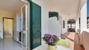 A balcony with a table, a chair, and a potted plant. - 3392 Dima Apartments - bilocale 1 by Barbarhouse (Melendugno)