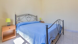 A single bed with a metal frame, a wooden nightstand with a lamp, and a plain wall. - 3392 Dima Apartments - bilocale 1 by Barbarhouse (Melendugno)