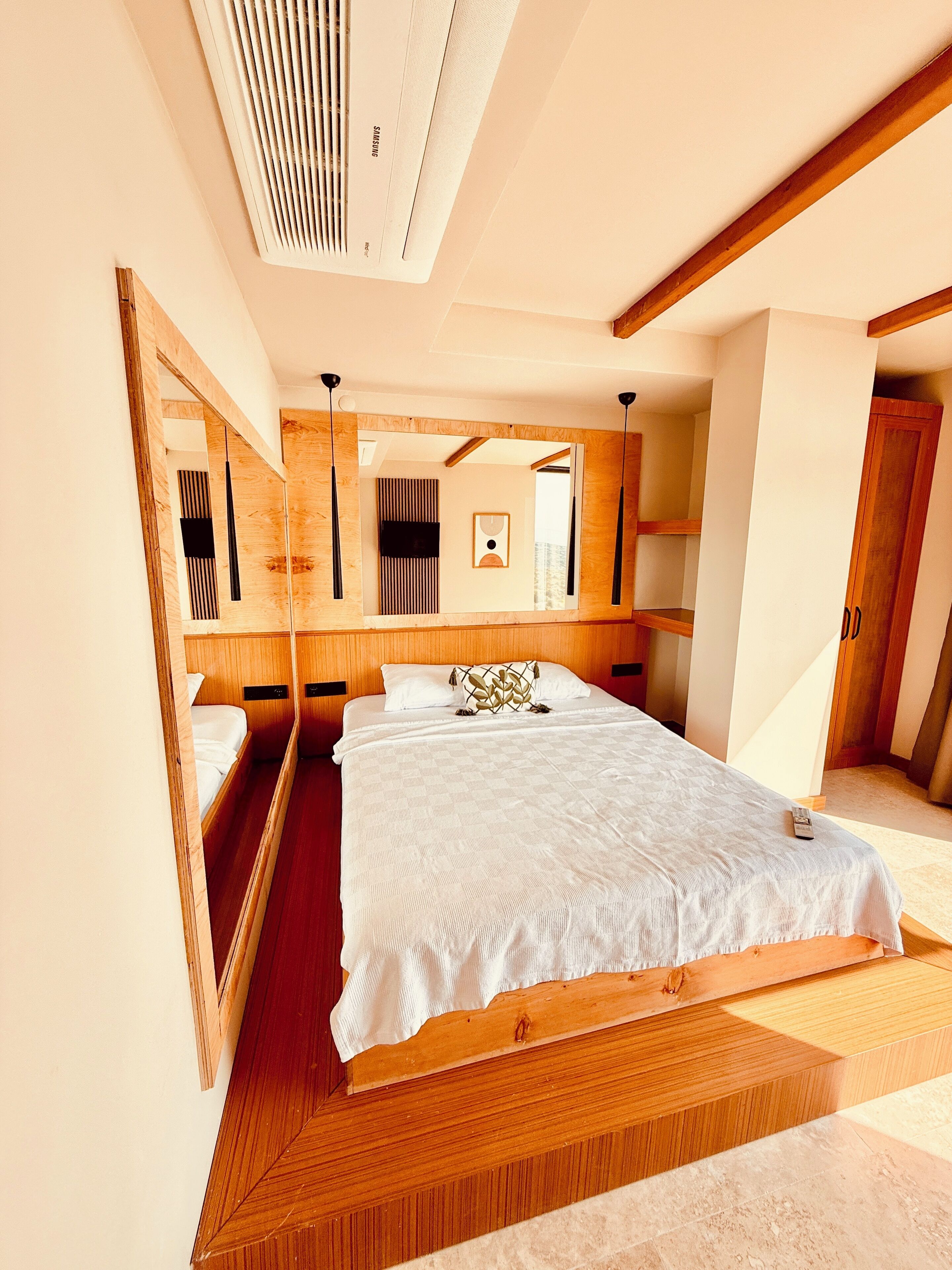 A modern bedroom with a large bed, wooden headboard, and built-in shelving.