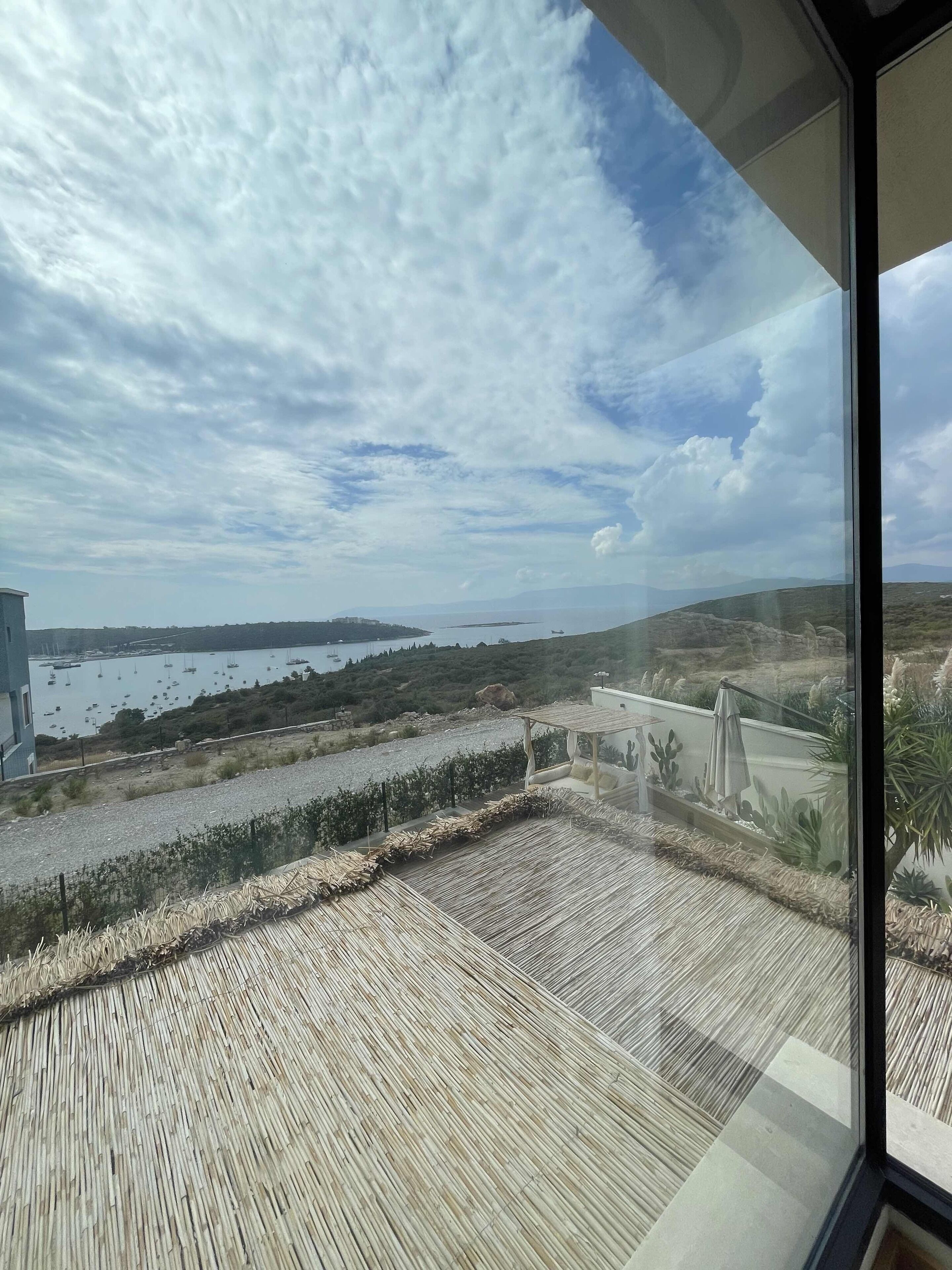 Una terraza con vistas a un cuerpo de agua, barcos y colinas distantes.