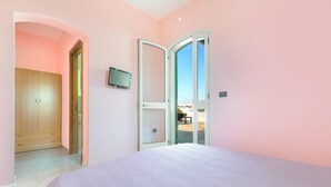 A bedroom with a bed, a wardrobe, a television, and a door leading to an outdoor area. - 3393 Dima Apartments - bilocale 2 by Barbarhouse (Melendugno)