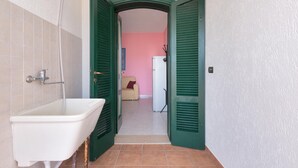 A bathroom with a white sink, green shutters, and a pink wall. - 3393 Dima Apartments - bilocale 2 by Barbarhouse (Melendugno)