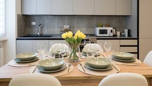 A modern kitchen with grey cabinets, a microwave, and a dining table set for six with plates and glasses. - [7 min from airport] Design house with A/C and WiFi (ciampino)