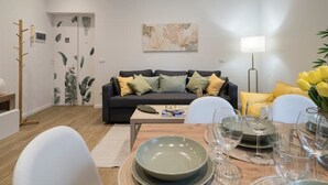 A modern living room with a dark sofa, a coffee table, and a dining area with a table set for two. - [7 min from airport] Design house with A/C and WiFi (ciampino)