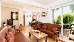 Ein geräumiges Wohnzimmer mit Ledersofas, einem Holztisch und einem Essbereich mit Stühlen und Tisch.