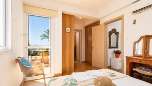 Ein Hotelzimmer mit Balkon, einem Bett mit Hut, einem Holzschrank und einem Spiegel.