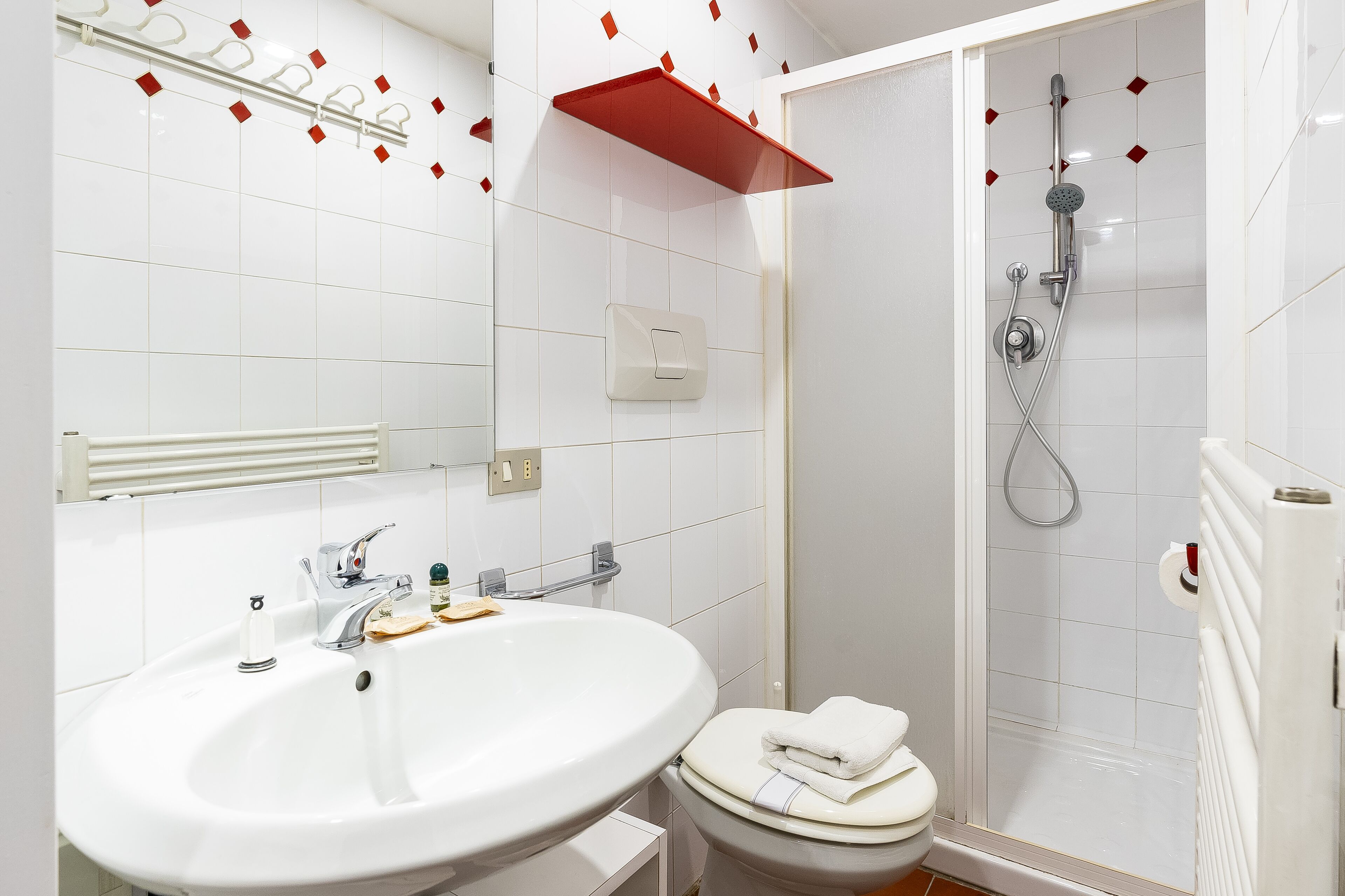 A bathroom with a white sink, toilet, and shower.