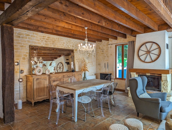 Un comedor rústico con una mesa de madera, sillas transparentes y una lámpara de araña.