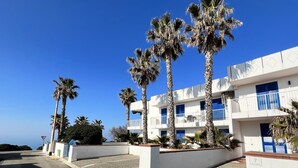 Un edificio blanco con balcones azules y palmeras.