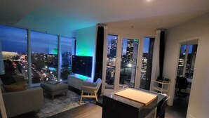 A modern living room with a pool table, a sofa, and a view of the city at night. - Lux Corner Unit-spa-gym-office-lounges (Montréal)