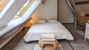 A bedroom with a sloped ceiling, skylight, a bed, a bedside table, and a chair. - "Le Clos de la Reine", Maison Avec Piscine (Josnes)