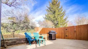 A backyard with a wooden fence, a barbecue grill, and two blue chairs. - WFH Private Suite kitchen & Yard (Sparks)