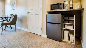 A compact kitchen with a microwave, refrigerator, and storage shelves. - WFH Private Suite kitchen & Yard (Sparks)