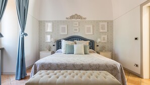 Een slaapkamer met een groot bed, een gestoffeerde bank, een hoofdbord en ingelijste foto's aan de muur.