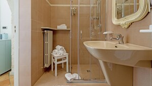 Een badkamer met een douche met glazen wand, een wastafel en een spiegel.
