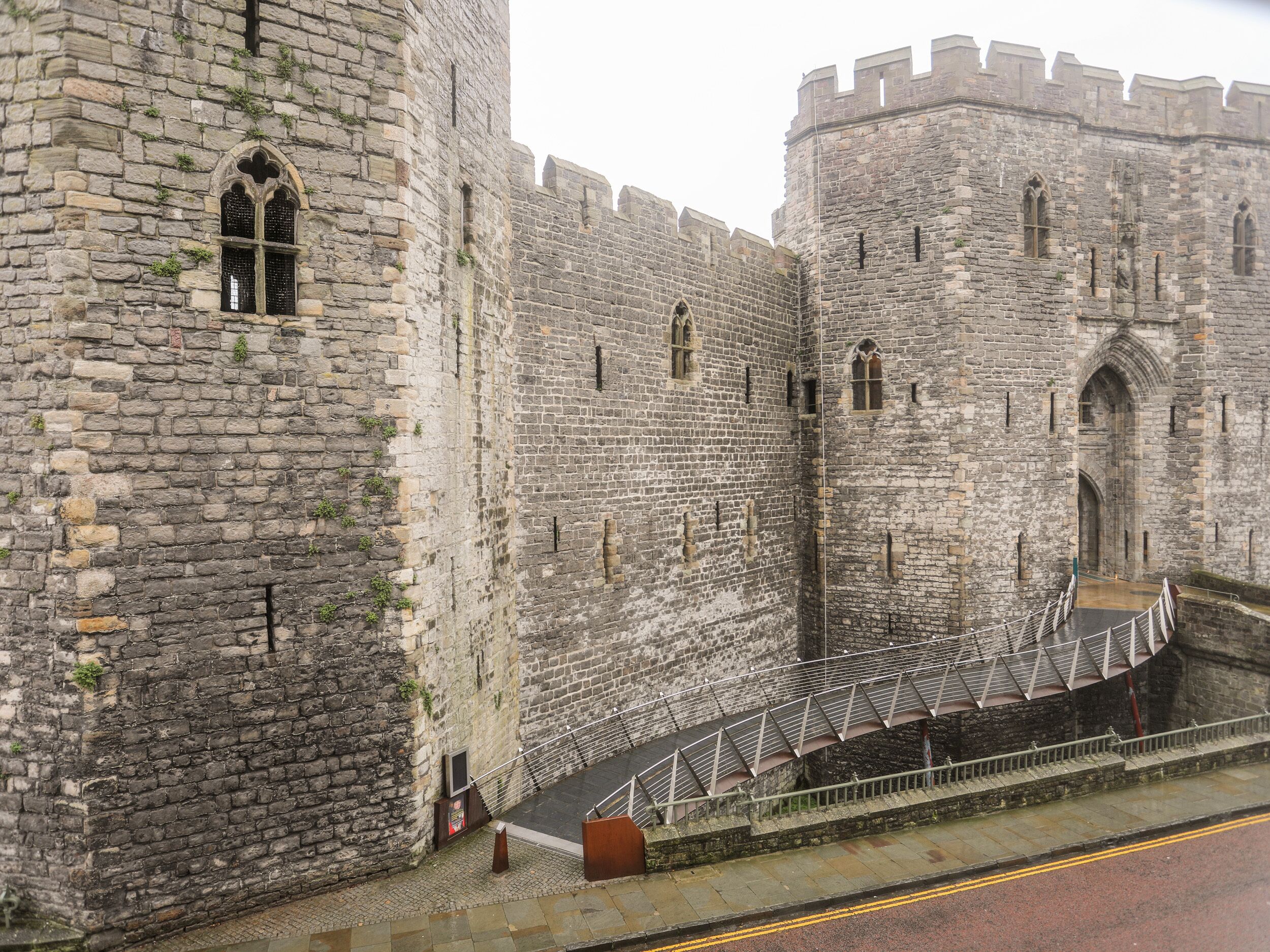 A historic stone castle with a central courtyard, a bridge leading to the entrance, and a guardhouse.