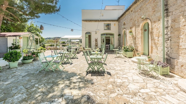 A courtyard with outdoor seating, stone flooring, and a building with arched windows. - 3520 Fabula Maison - Book (Monopoli)