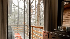 Une chambre dotée d’un grand lit, d’une commode en bois et d’une porte-fenêtre coulissante donnant sur un balcon agrémenté d’une balustrade en bois.