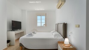 A hotel room with a bed, a desk with a TV, a window, and a bedside lamp. - Duquesa Regent Penthouse 2435 Sea-view Duplex (Manilva)
