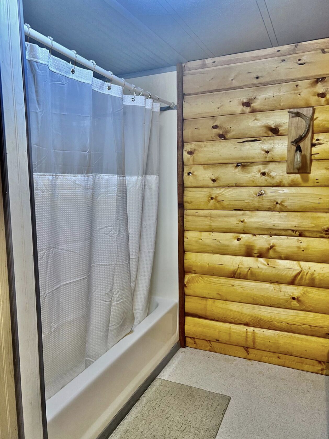 Ein Badezimmer mit Duschvorhang, Holzvertäfelung und einer Badewanne.