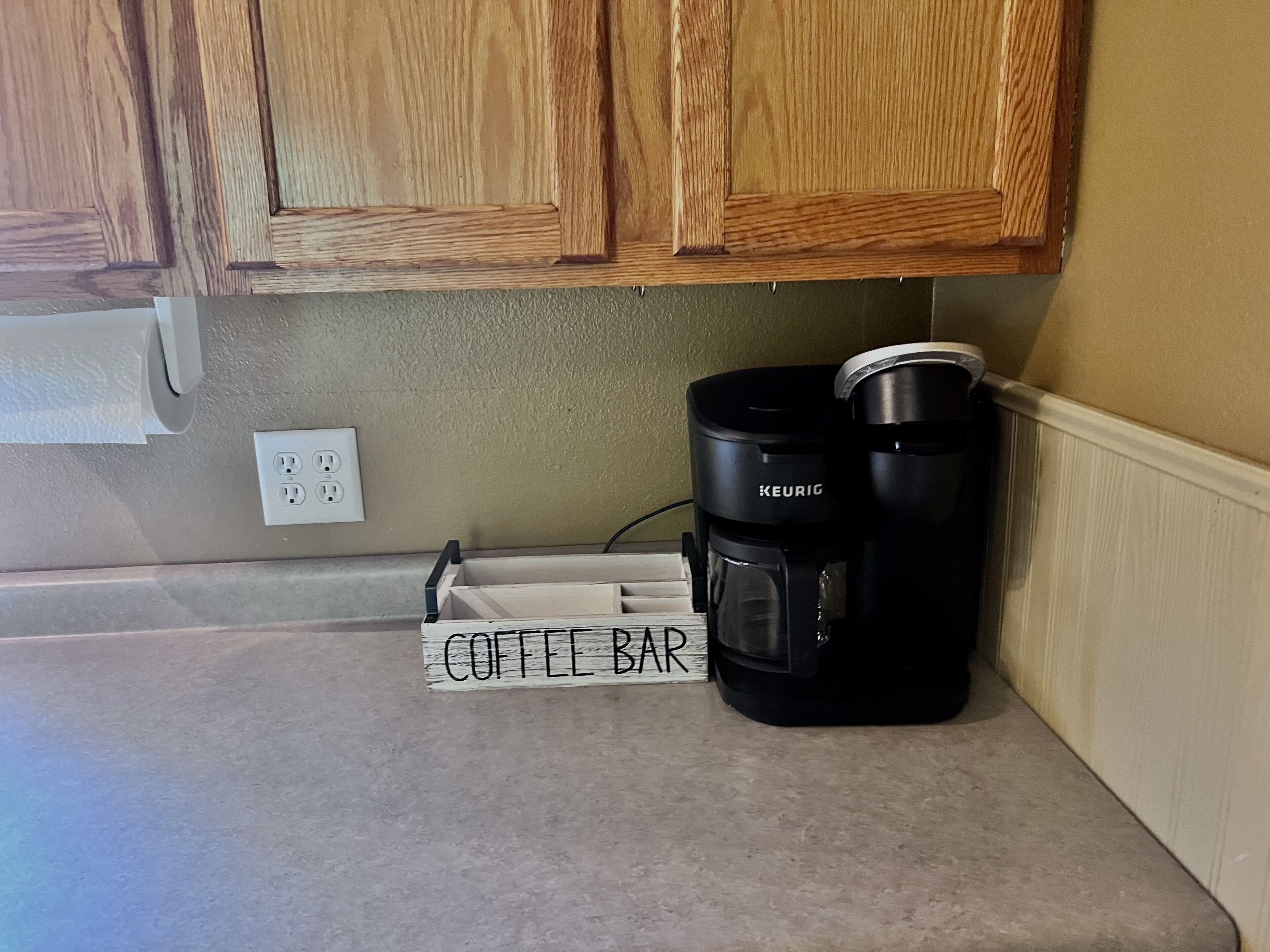 Una encimera de cocina con una cafetera y un letrero que dice 'Coffee Bar'.