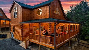 Uma cabana de toras com varanda, várias janelas e um deck.
