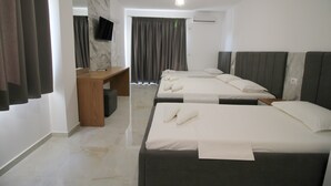 A hotel room with two beds, a desk, a television, and a shower area. - Hotel Four Islands (Ksamil)