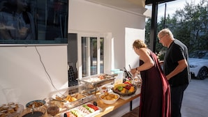A buffet table with various food items and a television screen displaying a show. - Hotel Four Islands (Ksamil)