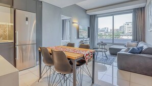 A modern apartment with a dining area, kitchen, and living space. - Luxury 1 Bed Apartment at The Capital on the Park (Johannesburg)
