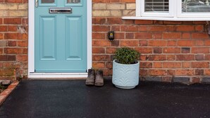 Een turquoise voordeur met een kleine plant er naast.