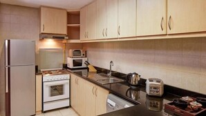 Cozinha compacta com geladeira, fogão, micro-ondas e torradeira.