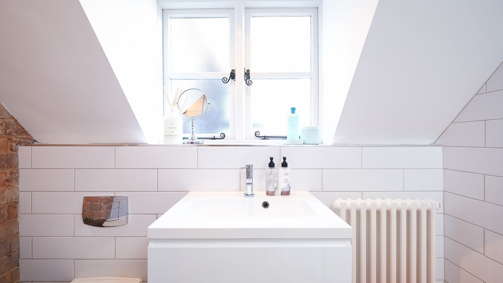 A modern bathroom with a white bathtub, a window above the sink, and a radiator.