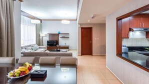 A modern hotel room with a dining area, a living room with a sofa and TV, and a kitchen with wooden cabinets. - Three Bedroom Apartment In Sadaf 3 Jbr By E R (Dubai)