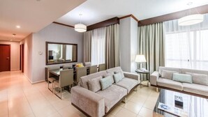 A modern living room with a sofa, a coffee table, and a dining area with chairs and a table. - Three Bedroom Apartment In Sadaf 3 Jbr By E R (Dubai)