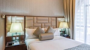 A hotel room with a large bed, two bedside tables with lamps, a headboard with a geometric pattern, and a window with curtains. - One Bedroom Apartment In Sadaf 3 Jbr By E R (Dubai)