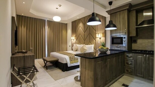 Habitació d'hotel moderna amb un llit gran, una cuineta i una zona de seients.